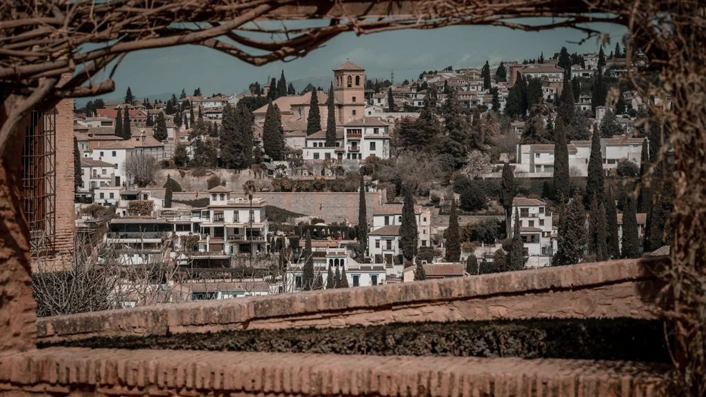 Cobbled street in Granada's Albaicín quarter with the Alhambra in the distance.